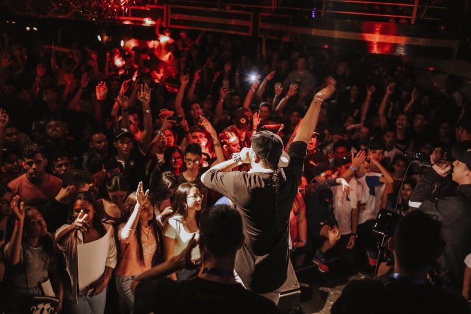 A dynamic image capturing the energy of a rap concert, with performers on stage and a crowd of enthusiastic fans.
